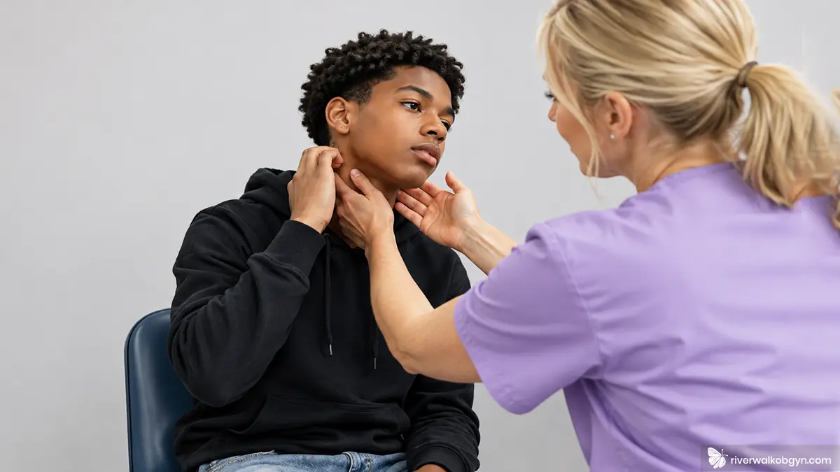 Nurse with blonde hair checking African American male teen neck for mononucleosis symptoms